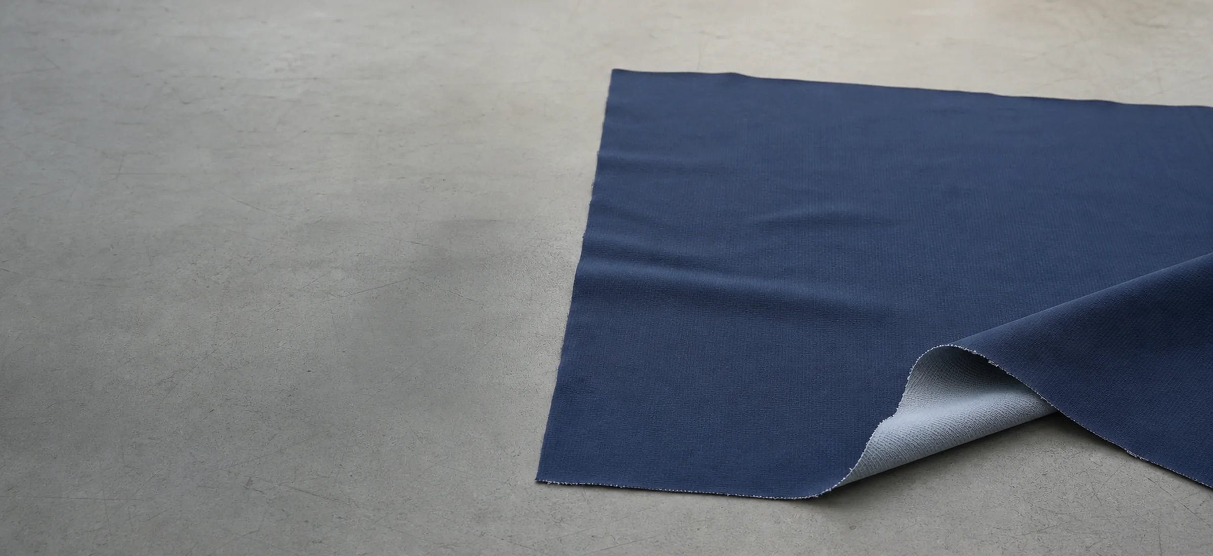 A panel of cycling jersey fabric laid flat on a pattern table, one lower corner lifted to show the reverse face underneath