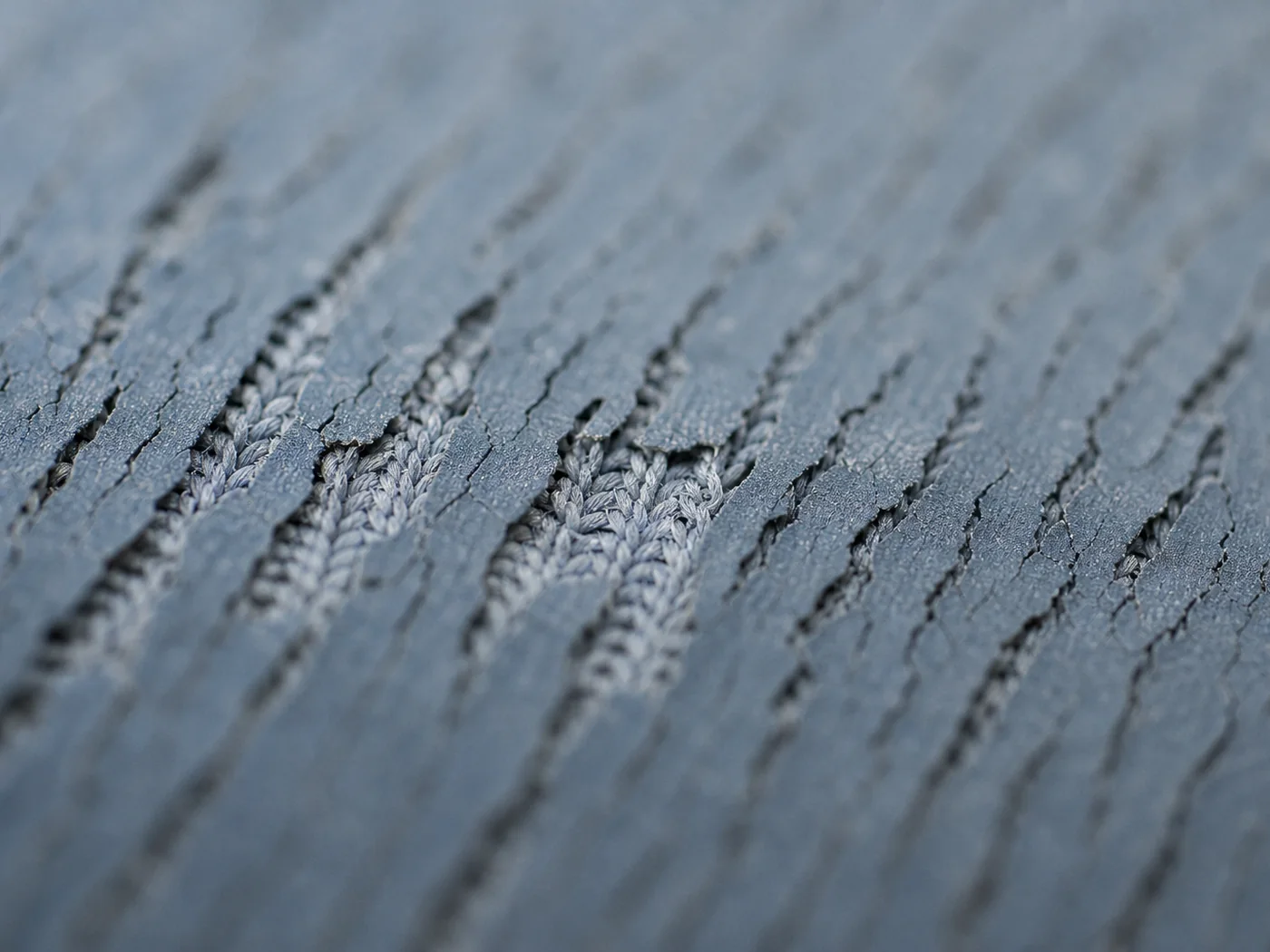 Macro view of four-way stretch knit under tension, the surface coating on it breaking into fine cracks